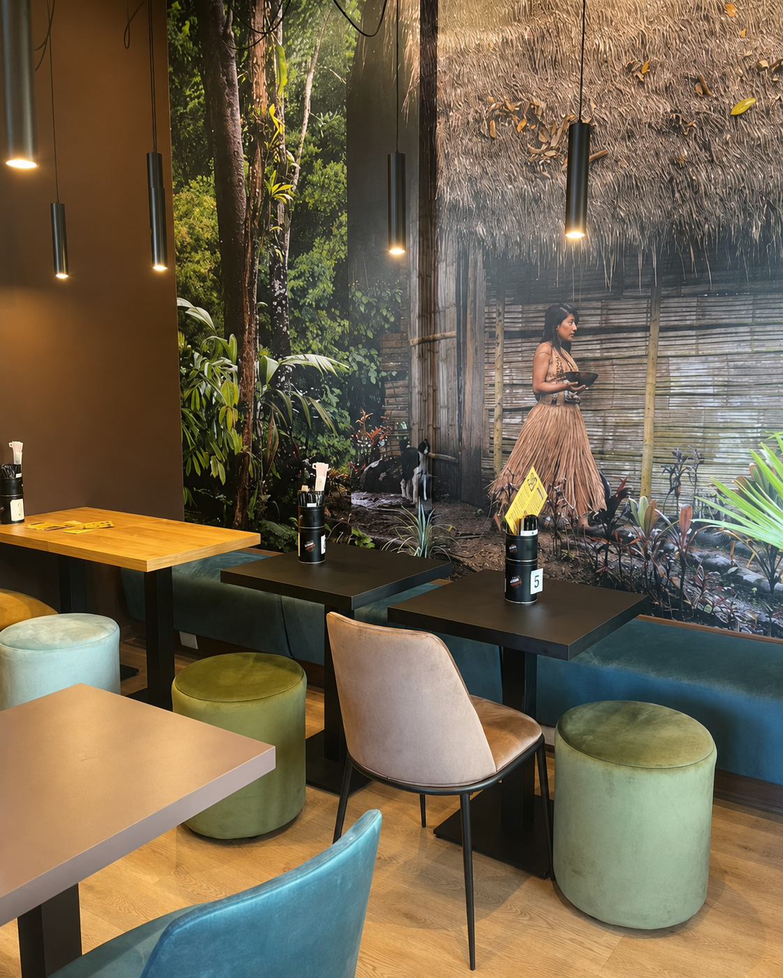 Tavoli della caffetteria NINA KAKAW con la parete che raffigura la foresta amazzonica