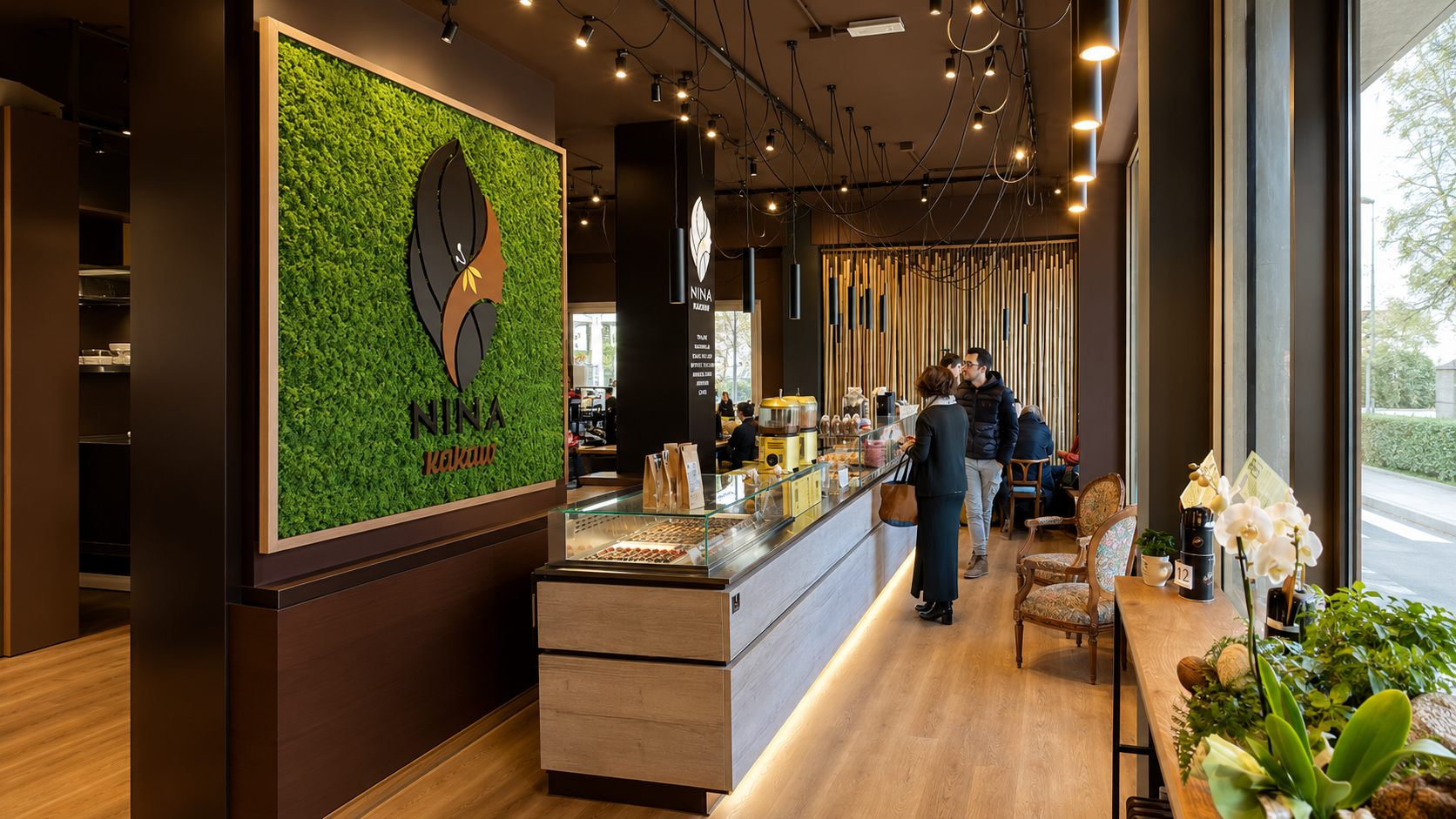 Interno della caffetteria e cioccolateria NINA KAKAW a Belluno con il logo verde, il banco e la vetrina delle praline