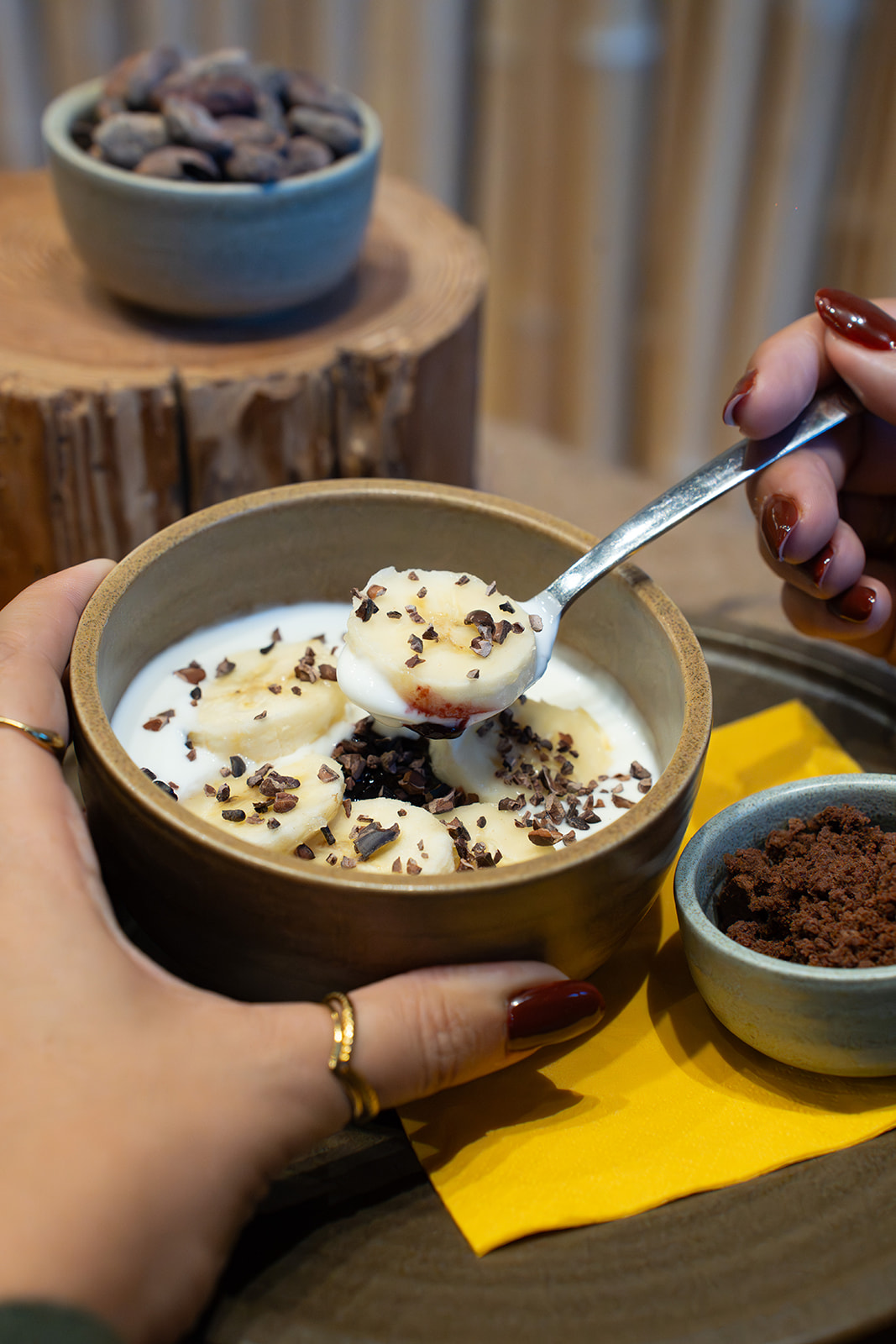 Ciotola di yogurt con banana e granella di cacao servita a colazione da NINA KAKAW a Belluno