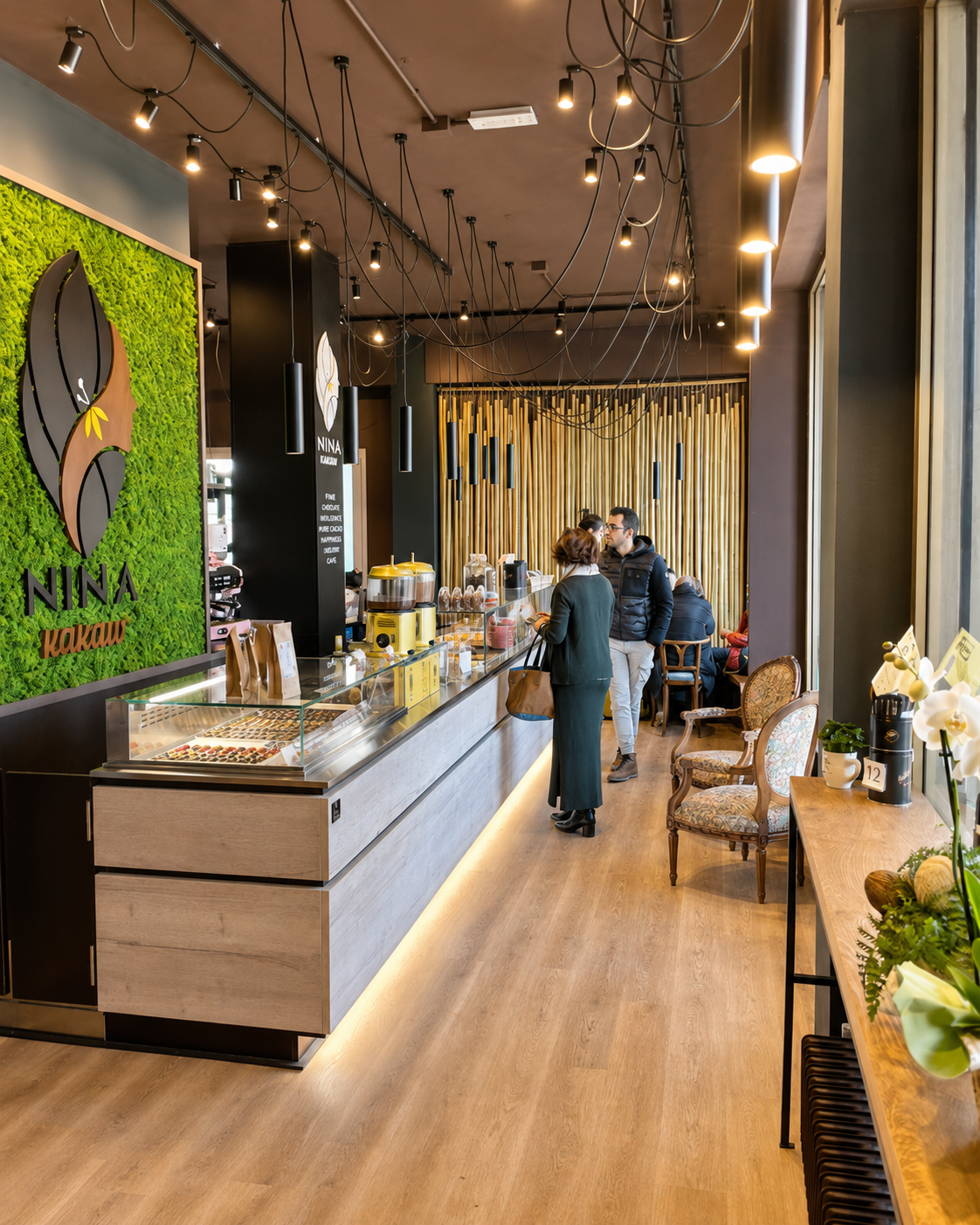Sala della cioccolateria NINA KAKAW a Belluno con banco e parete verde con il logo
