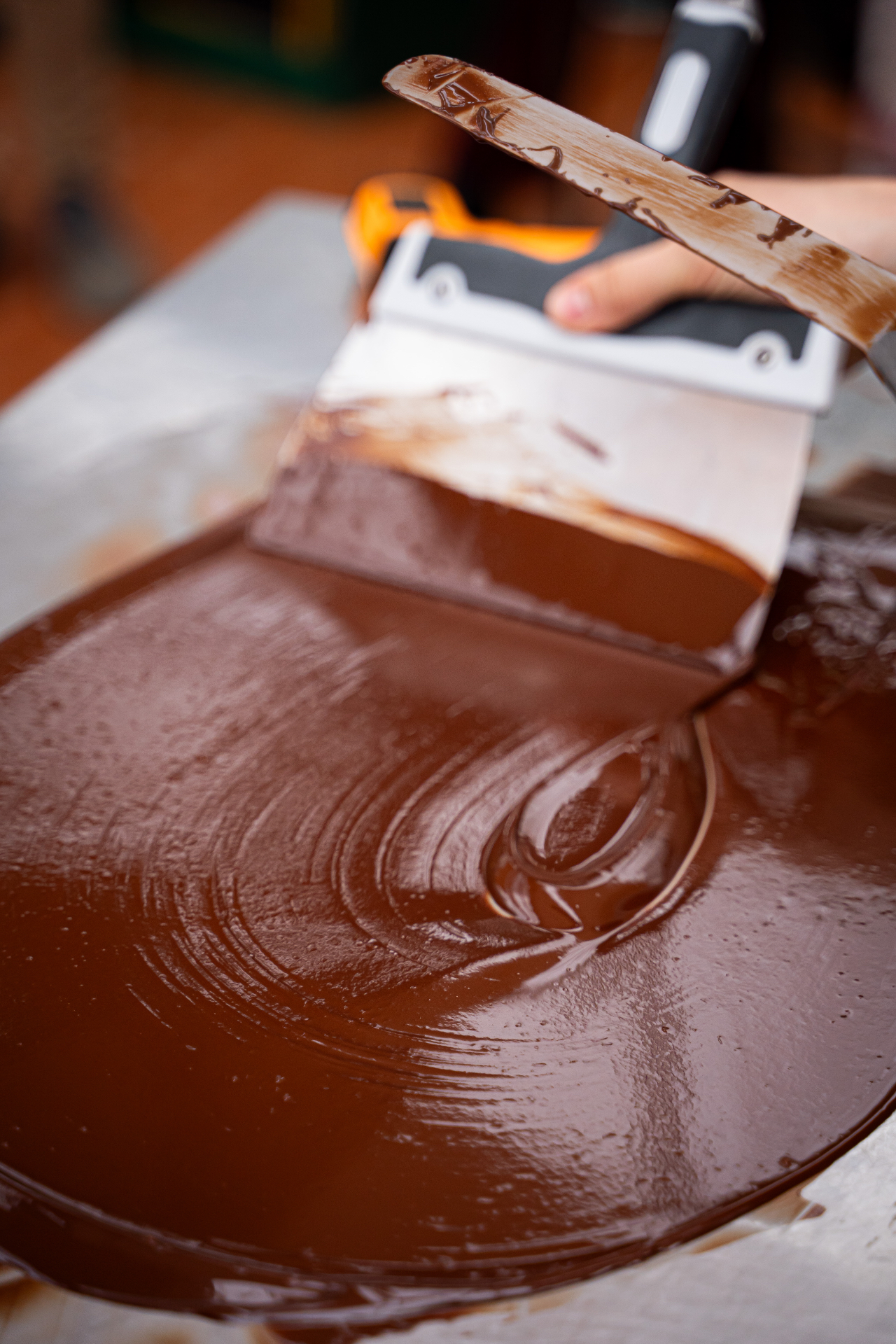 Temperaggio del cioccolato NINA KAKAW: spatola che lavora il cioccolato lucido sul piano di marmo