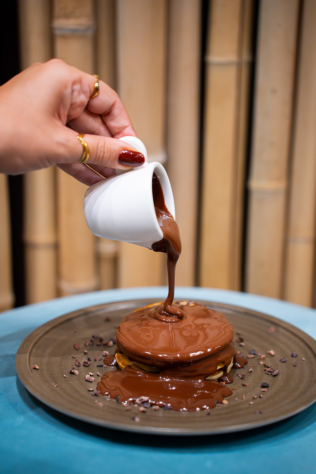 Cioccolato fuso versato su pancake con granella di cacao NINA KAKAW