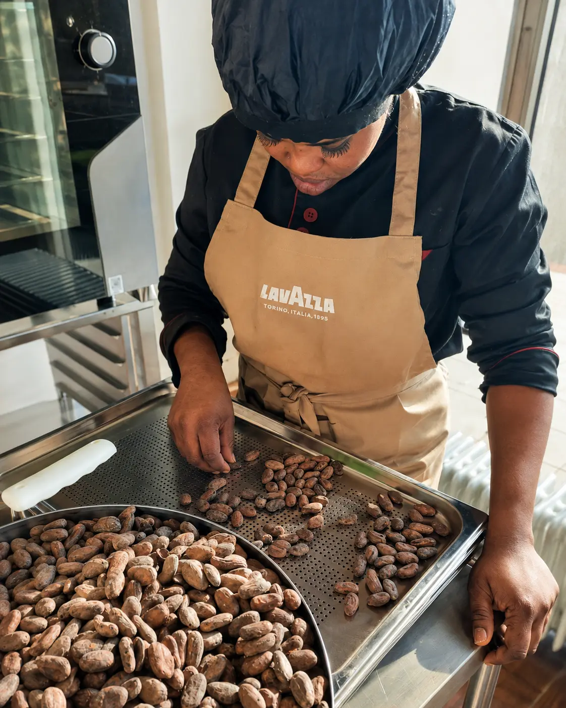Operatrice che seleziona a mano le fave di cacao nel laboratorio di Belluno